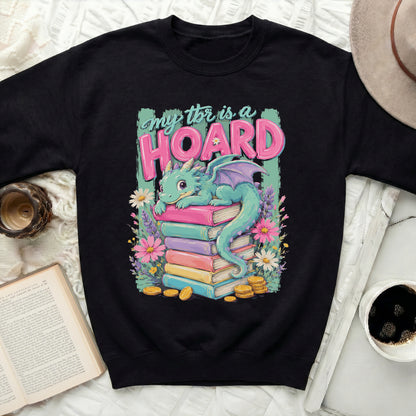 Black sweatshirt with a cute dragon sitting on a stack of colorful books.