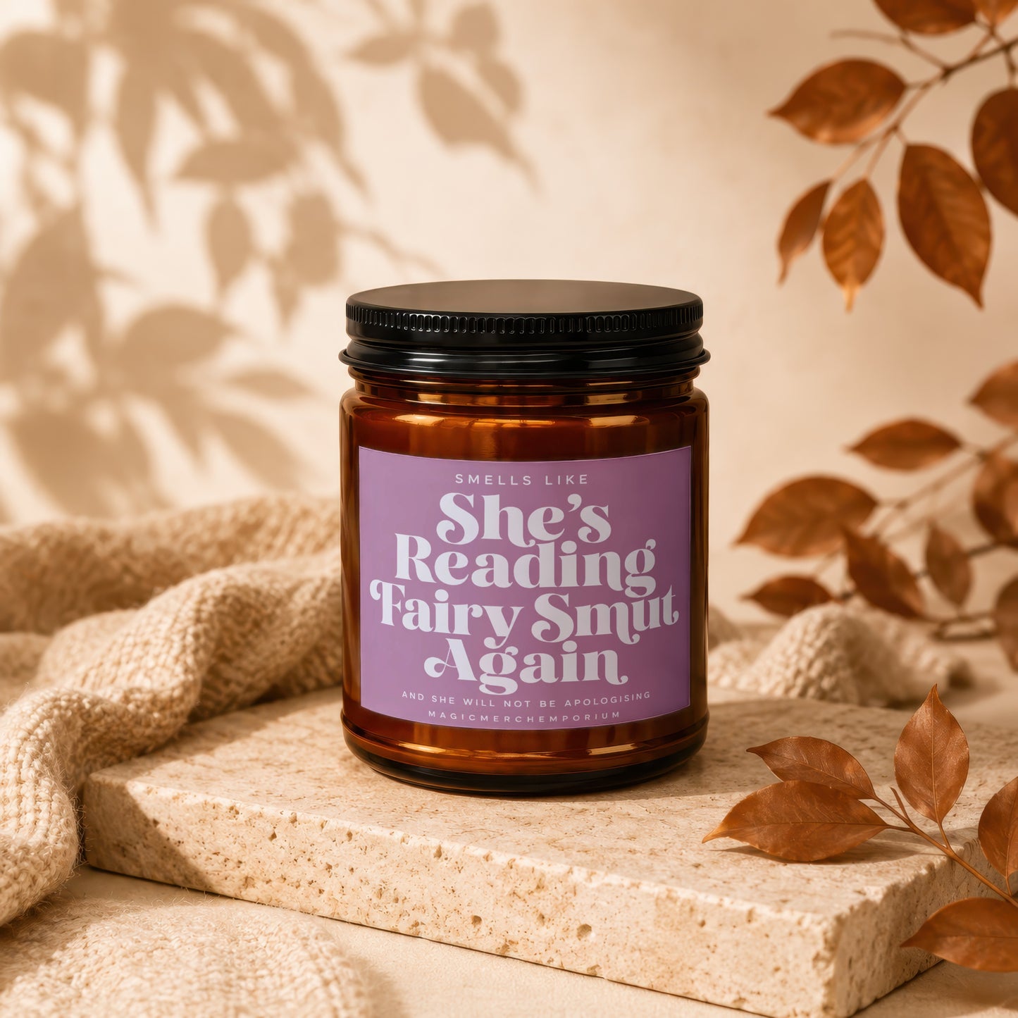 Brown candle with purple label reading "She's Reading Fairy Smut Again".