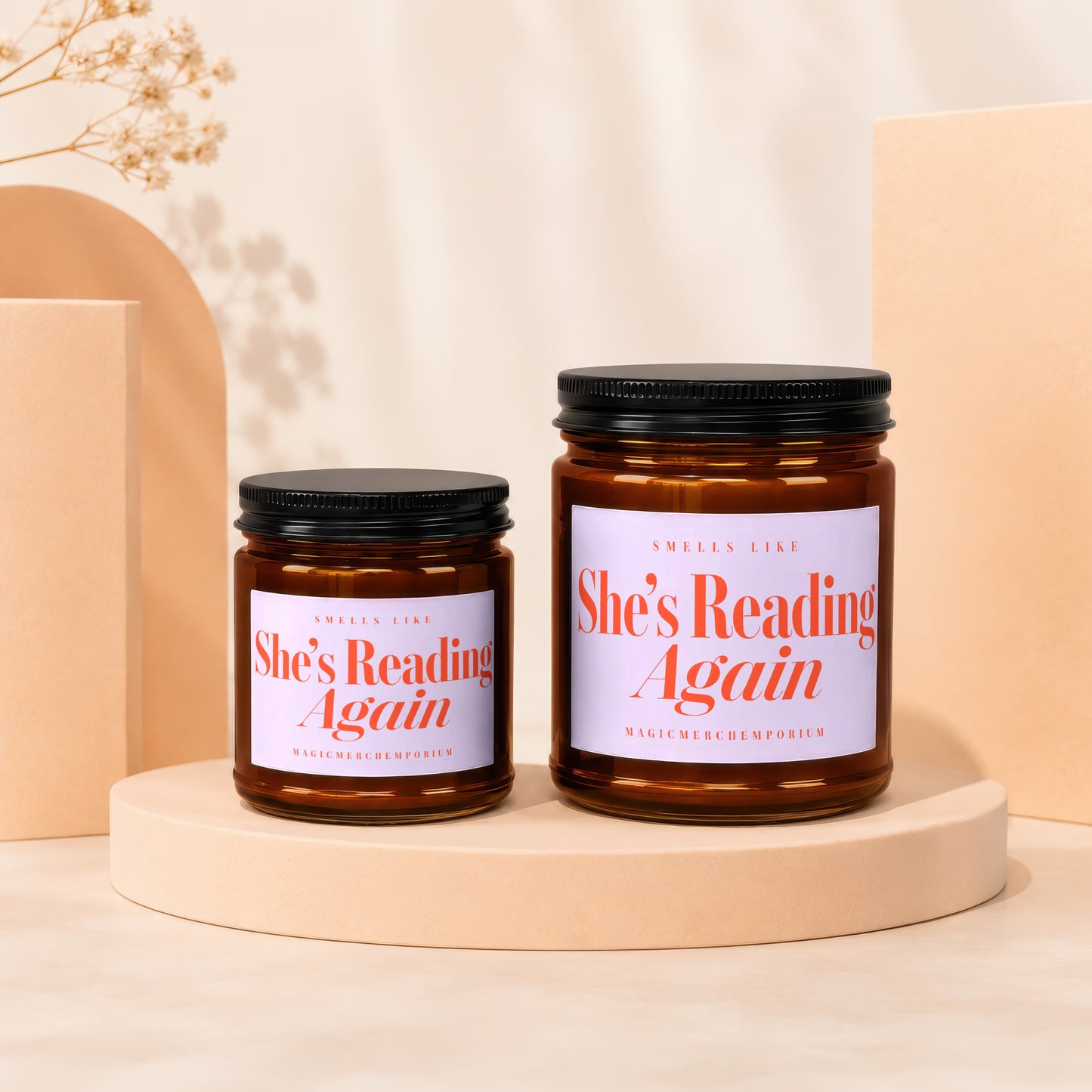 Two glass jar candles with "She's Reading Again" text on labels.