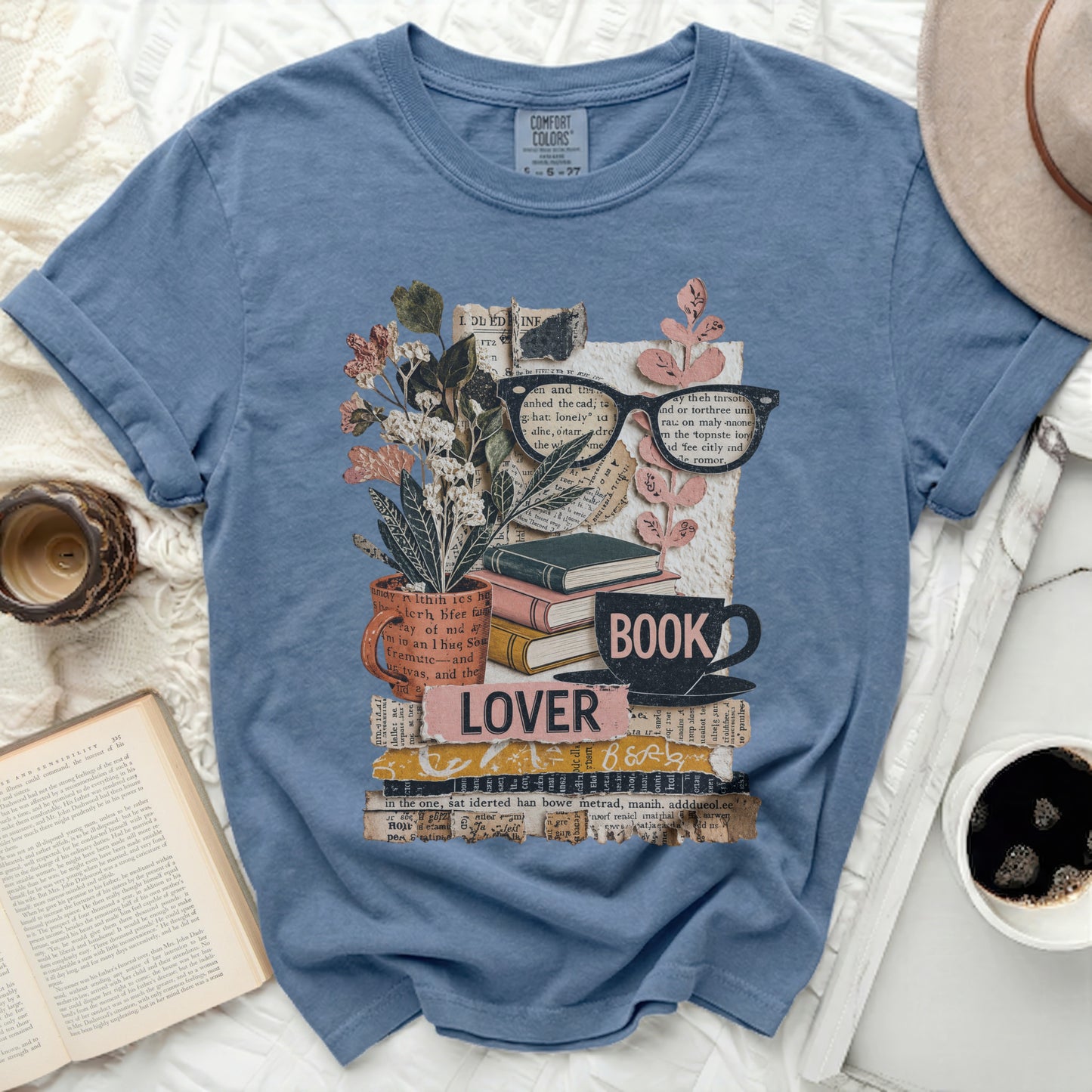 Blue t-shirt with a collage of books, glasses, flowers, and the word "LOVER".