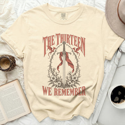 T-shirt with sword, dragons, flowers, and text "The Thirteen We Remember".