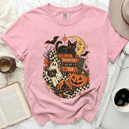 Pink t-shirt with Halloween graphic: black cat on books reading "HAUNTED BY MY TBR".