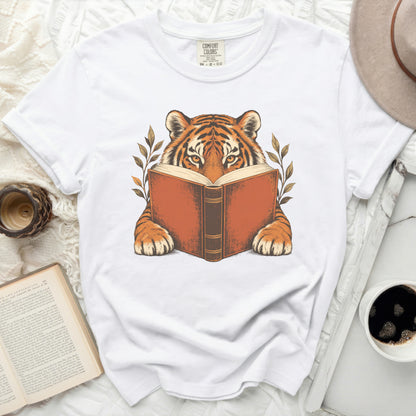 White t-shirt featuring a tiger reading a book, surrounded by leaves.
