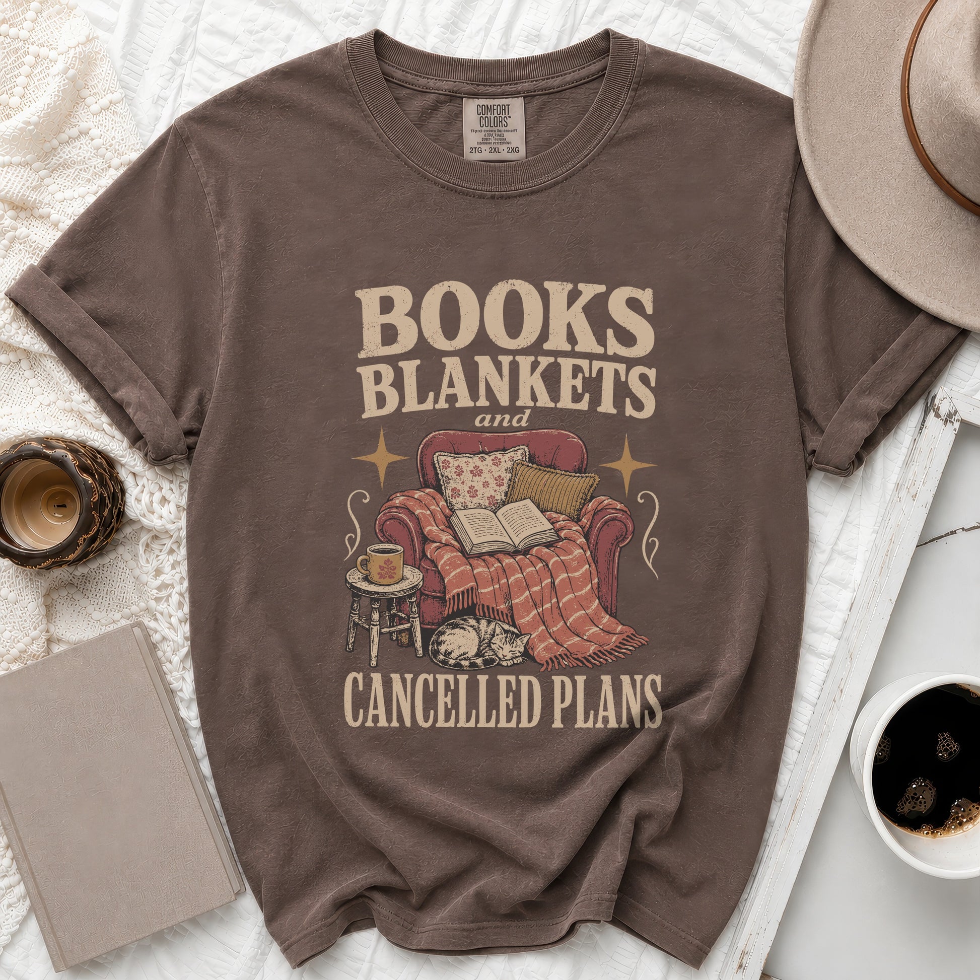 Brown t-shirt with "Books Blankets and Cancelled Plans" text and cozy scene.