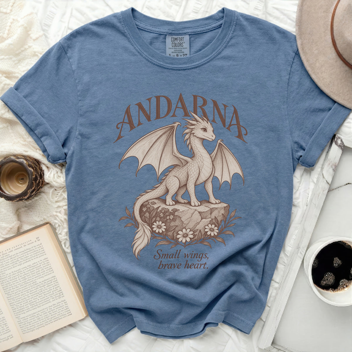 Blue t-shirt with a dragon graphic and the text "ANDARNA" and "Small wings, brave heart."