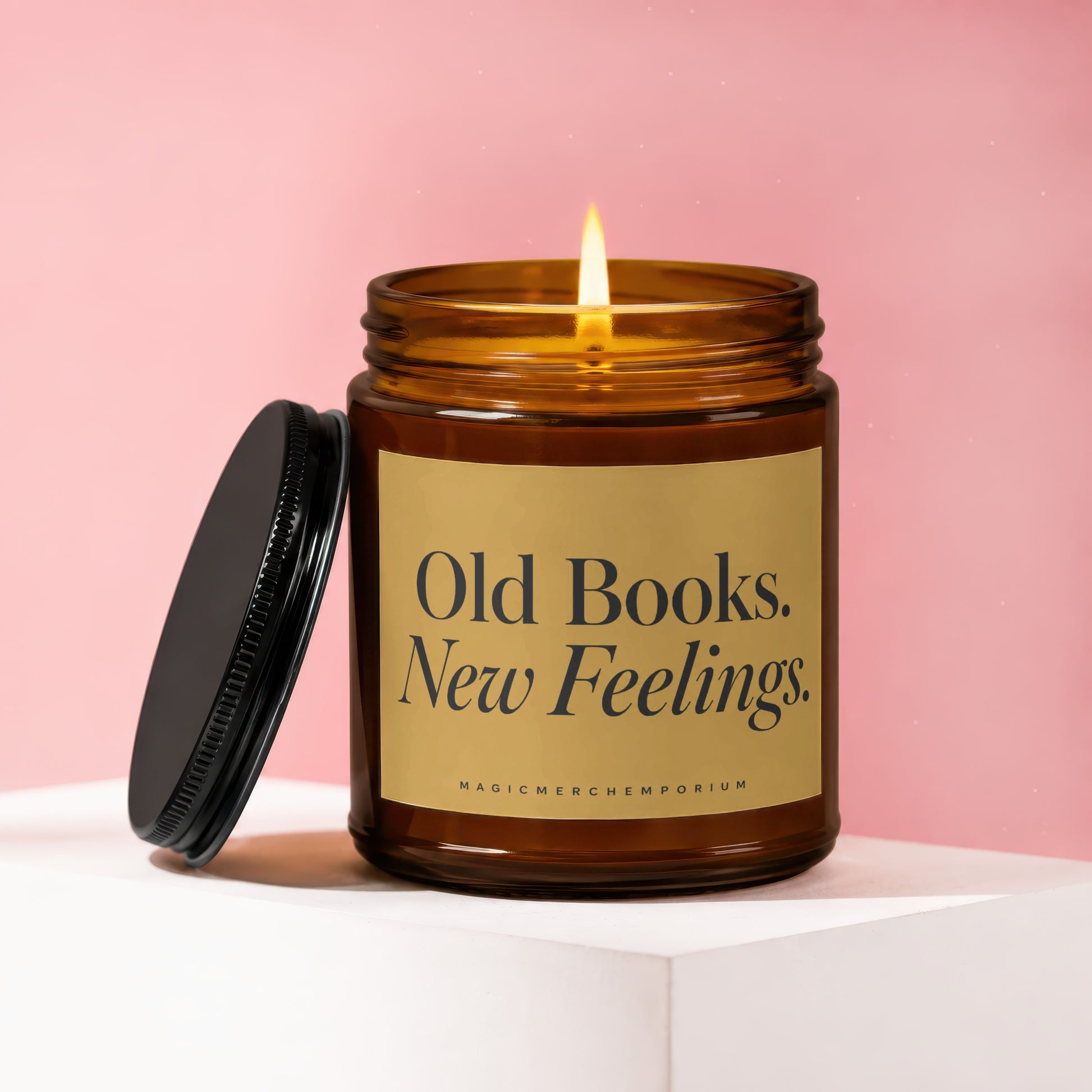 Amber glass candle with lit flame, black lid, and "Old Books. New Feelings." text.