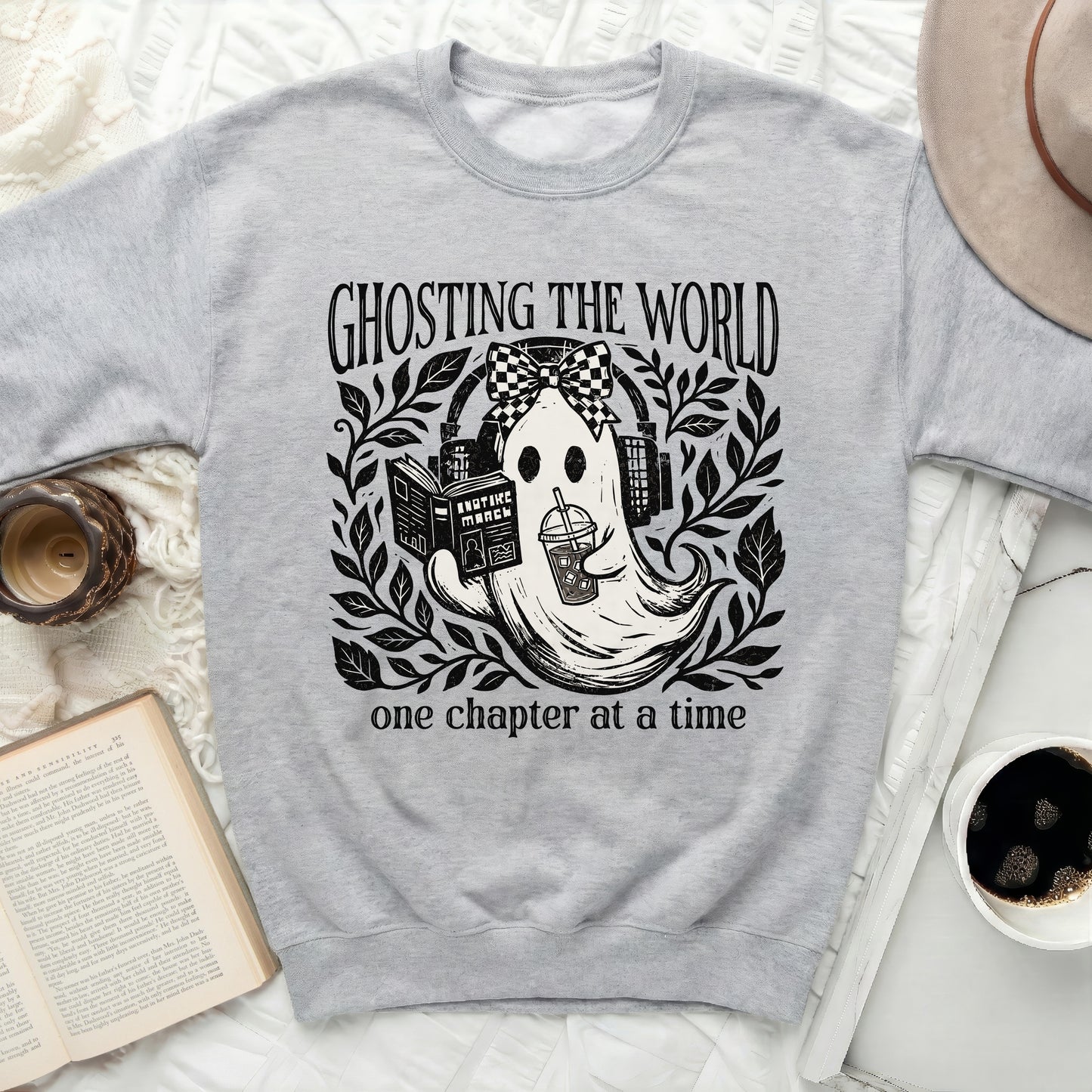 Grey sweatshirt with a graphic of a ghost reading and drinking, with text "GHOSTING THE WORLD one chapter at a time".