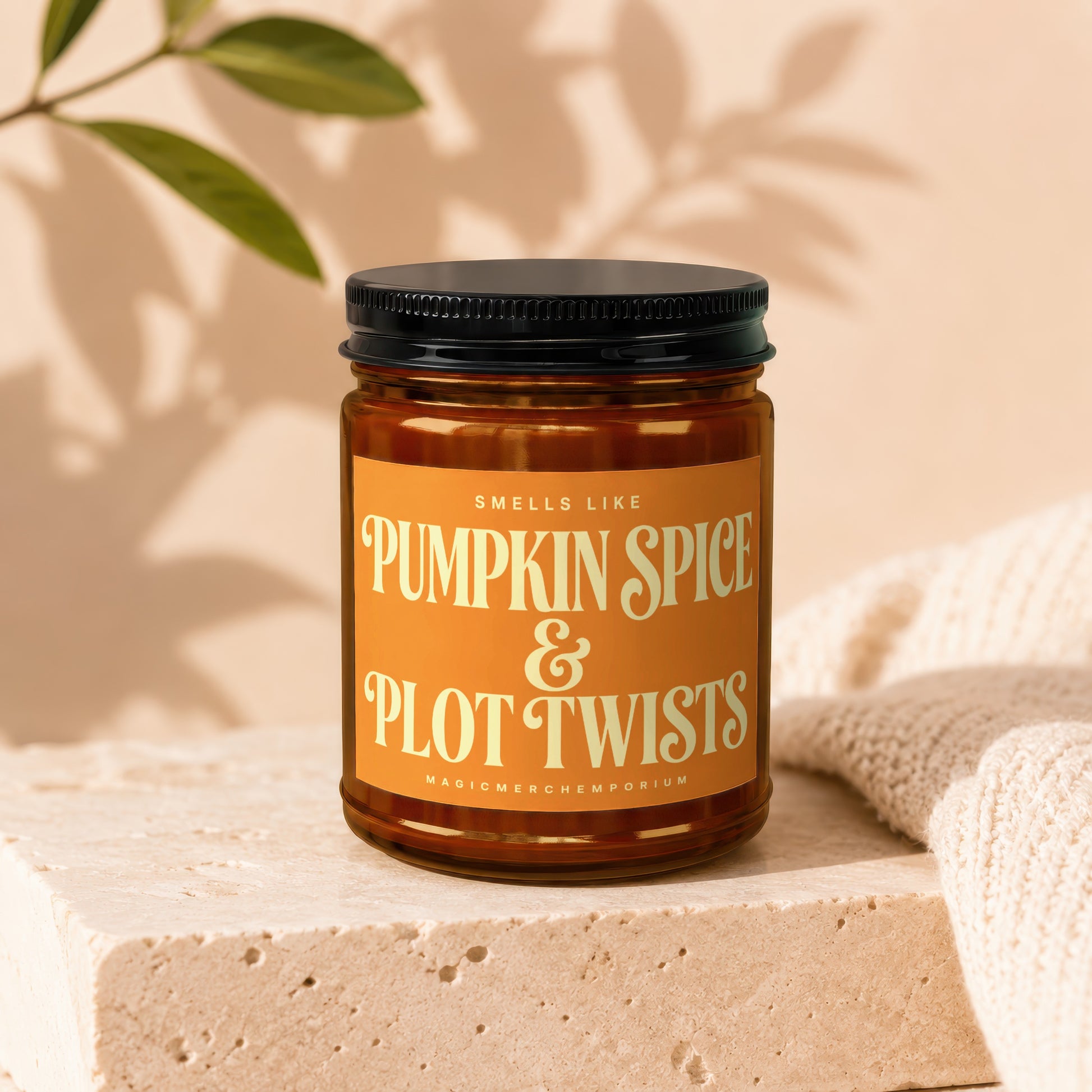 Amber jar candle labeled "Smells Like Pumpkin Spice & Plot Twists".