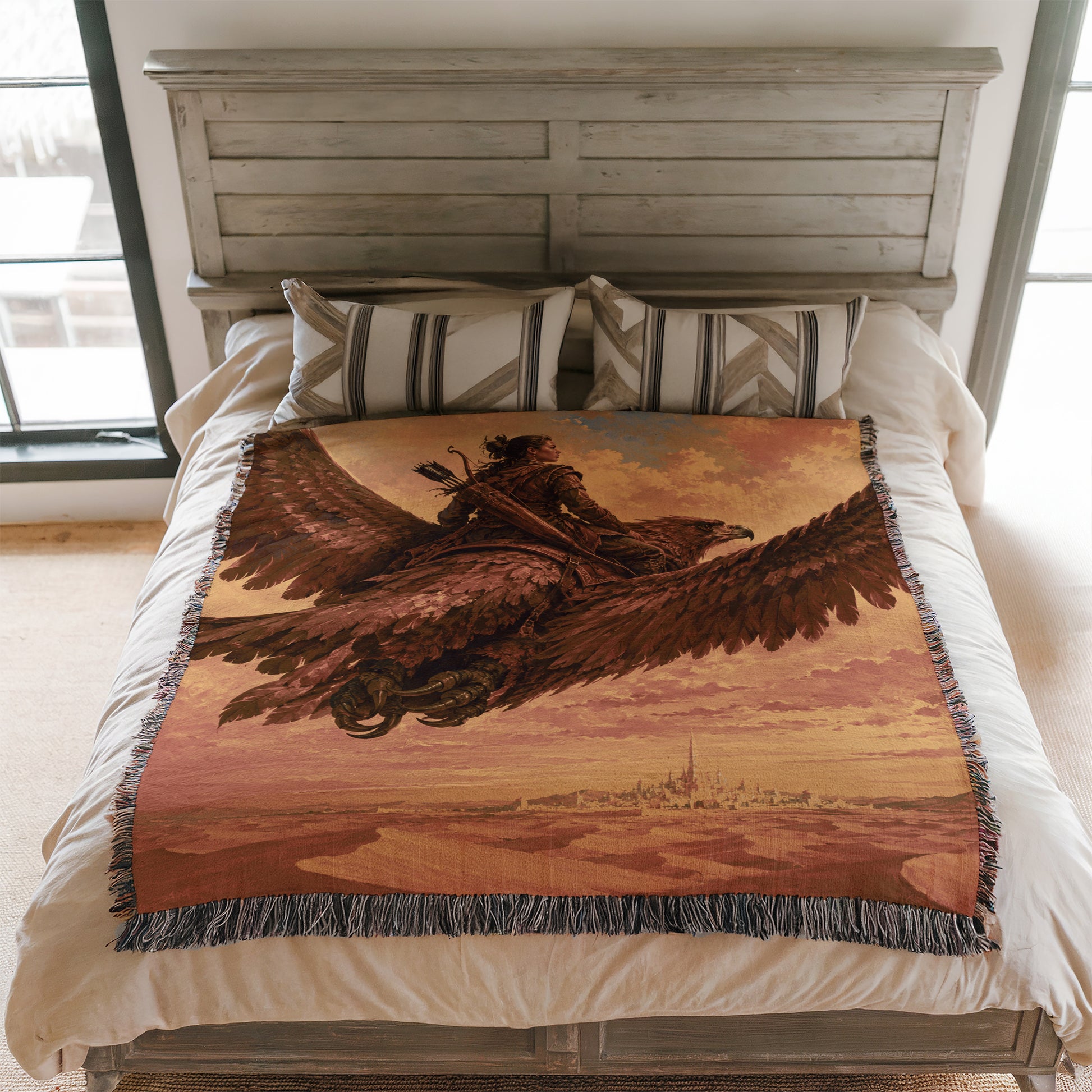 a bed with a large blanket that depicts a person riding a winged creature, possibly a dragon or a mythical bird. The blanket is spread over the bed, covering the entire surface.