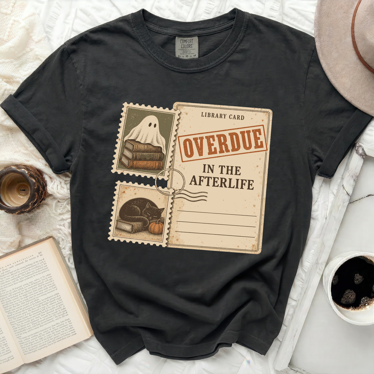 Black t-shirt with a library card graphic featuring a ghost, cat, and "OVERDUE IN THE AFTERLIFE" text.