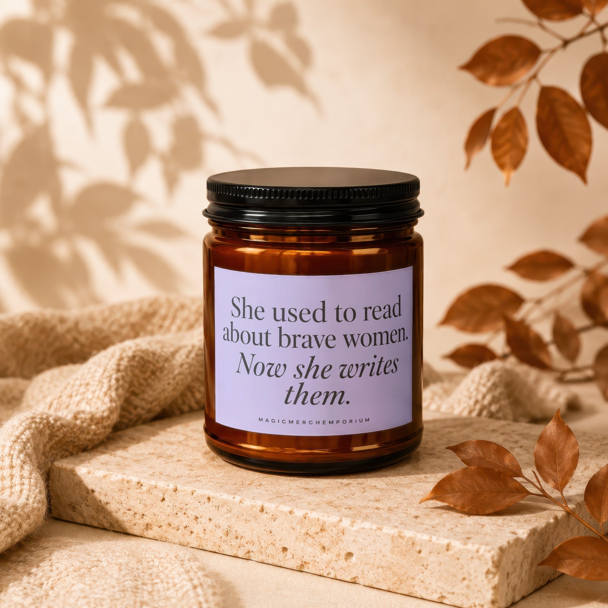 Candle with label reading "She used to read about brave women. Now she writes them."