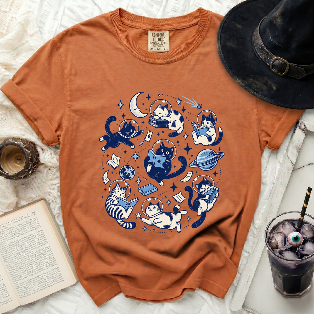 Orange t-shirt with astronaut cats reading books in space graphic.