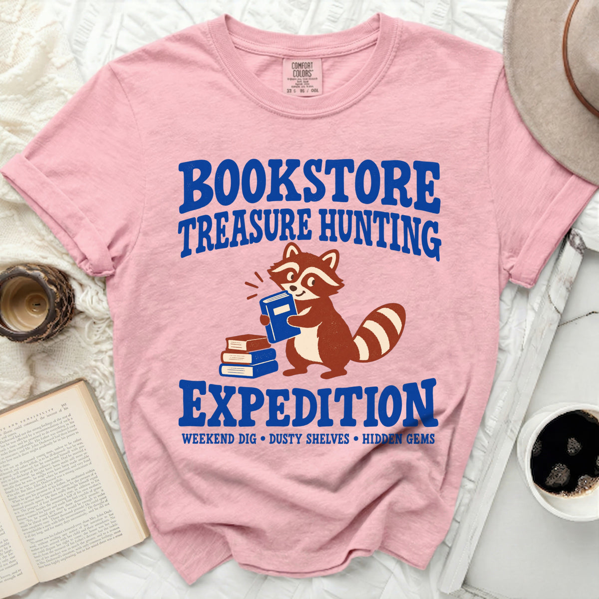 Pink t-shirt with "Bookstore Treasure Hunting Expedition" graphic and raccoon.