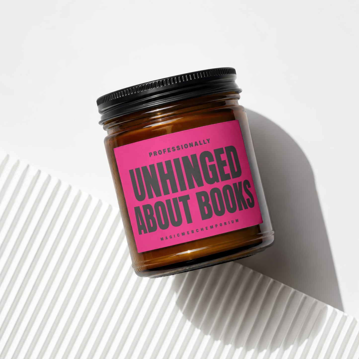 Amber jar candle with pink label reading "Professionally Unhinged About Books".