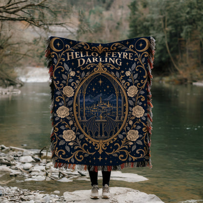 Hello Feyre Darling Crest Woven Throw Blanket held up by a river