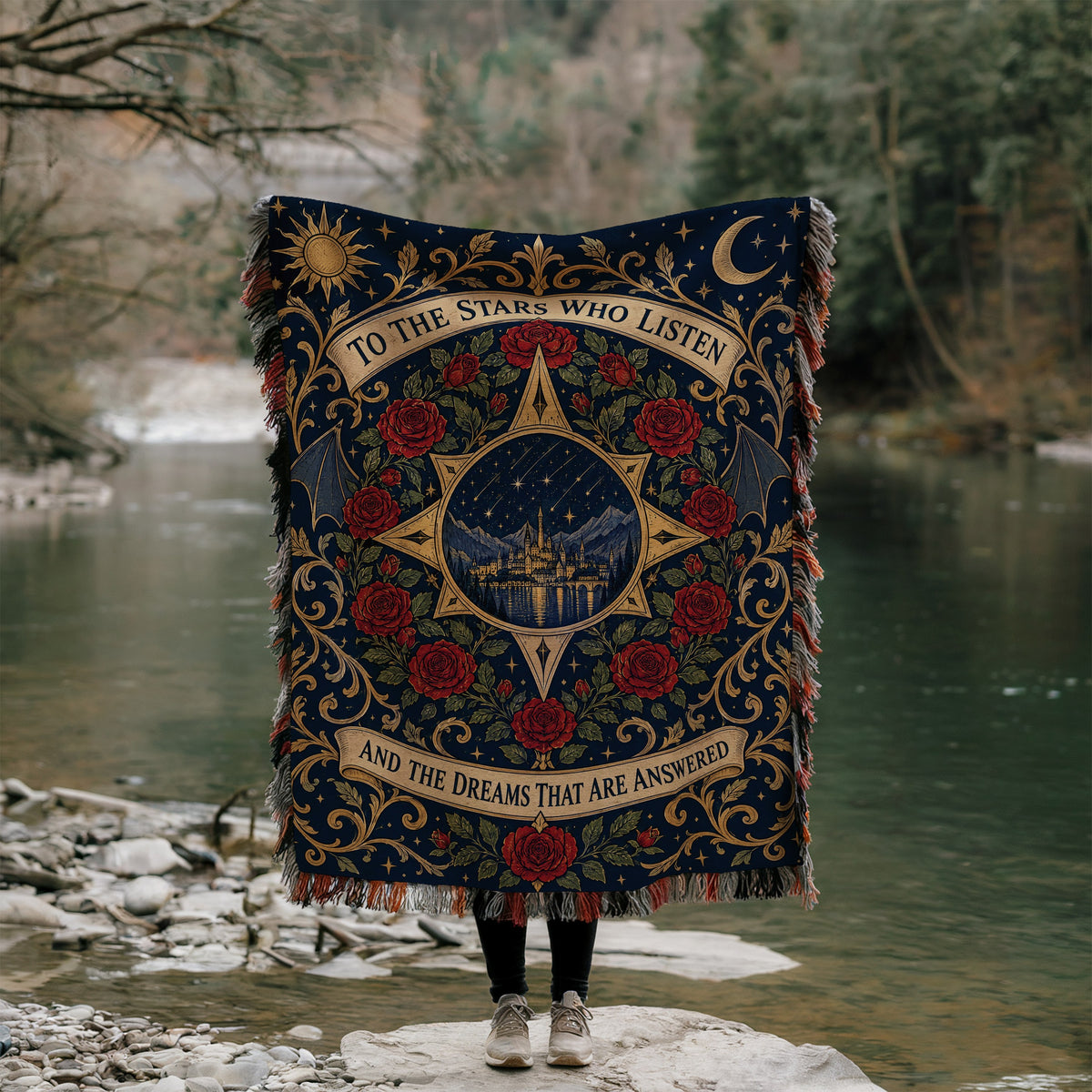 To The Stars Who Listen Rose Crest Woven Throw Blanket held up by a river