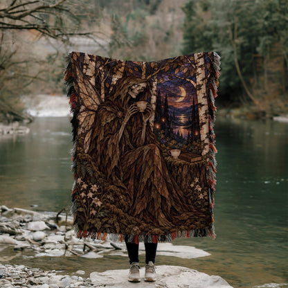 Suriel Tea Woven Throw Blanket held up outdoors by a river