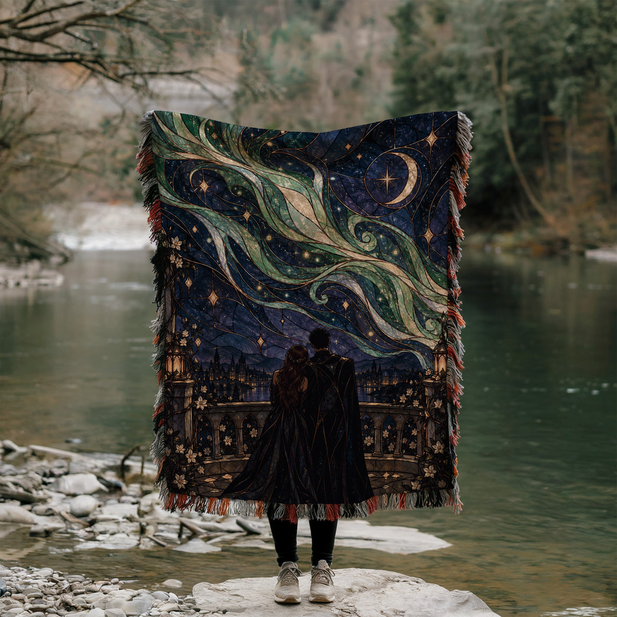 Starfall Stained Glass Woven Throw Blanket held up outdoors by a river