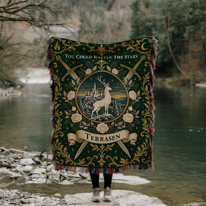 Terrasen Crest Woven Throw Blanket held up by a river