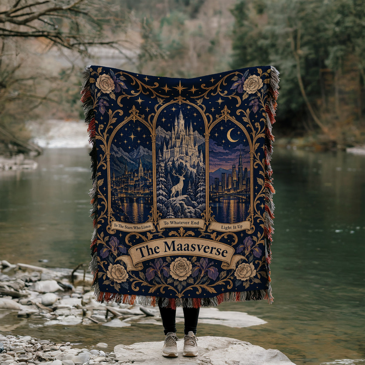 Maasverse Three Realms Crest Woven Throw Blanket held up by a river