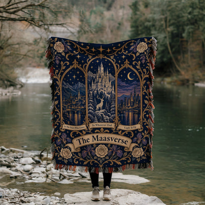 Maasverse Three Realms Crest Woven Throw Blanket held up by a river