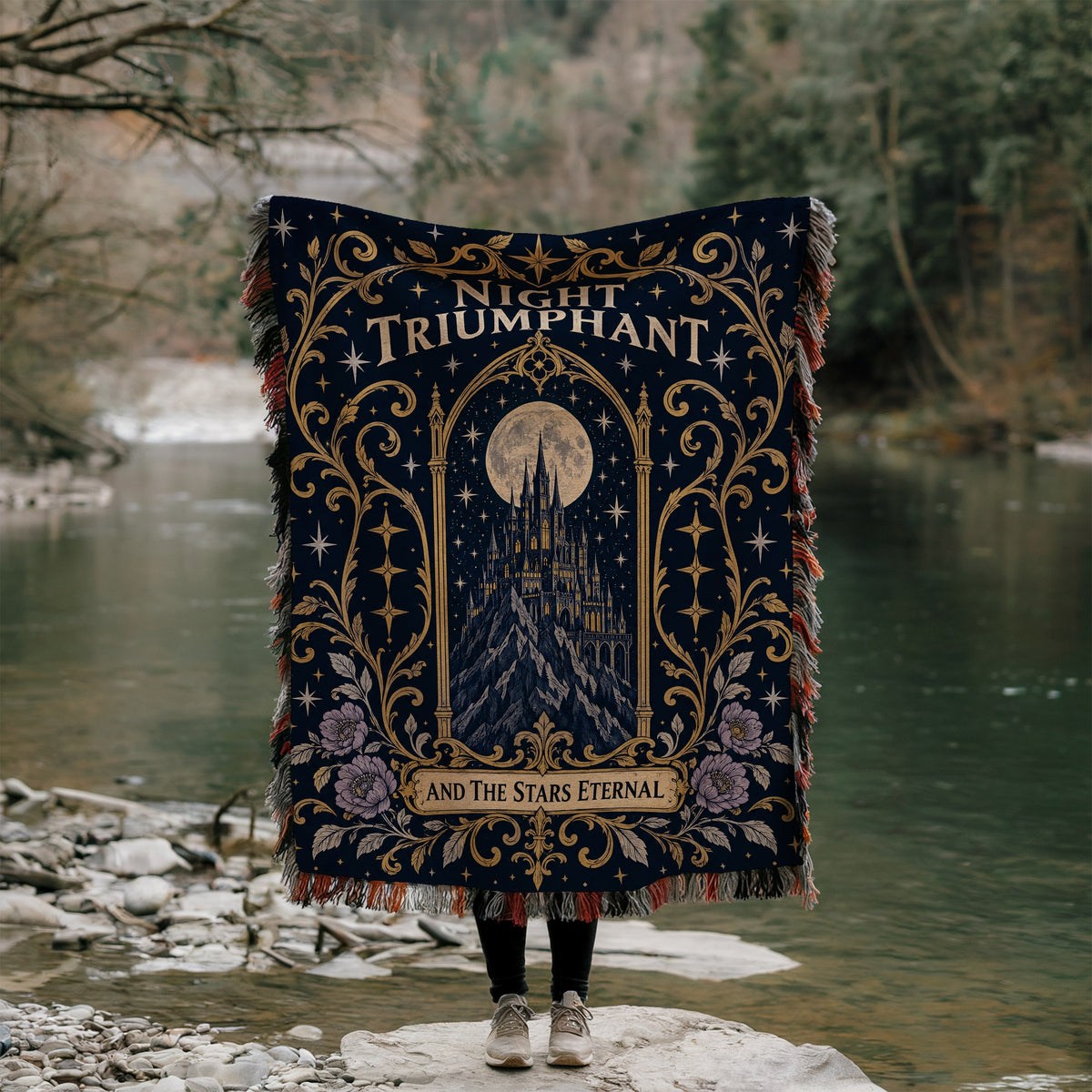 Night Triumphant Crest Woven Throw Blanket held up by a river