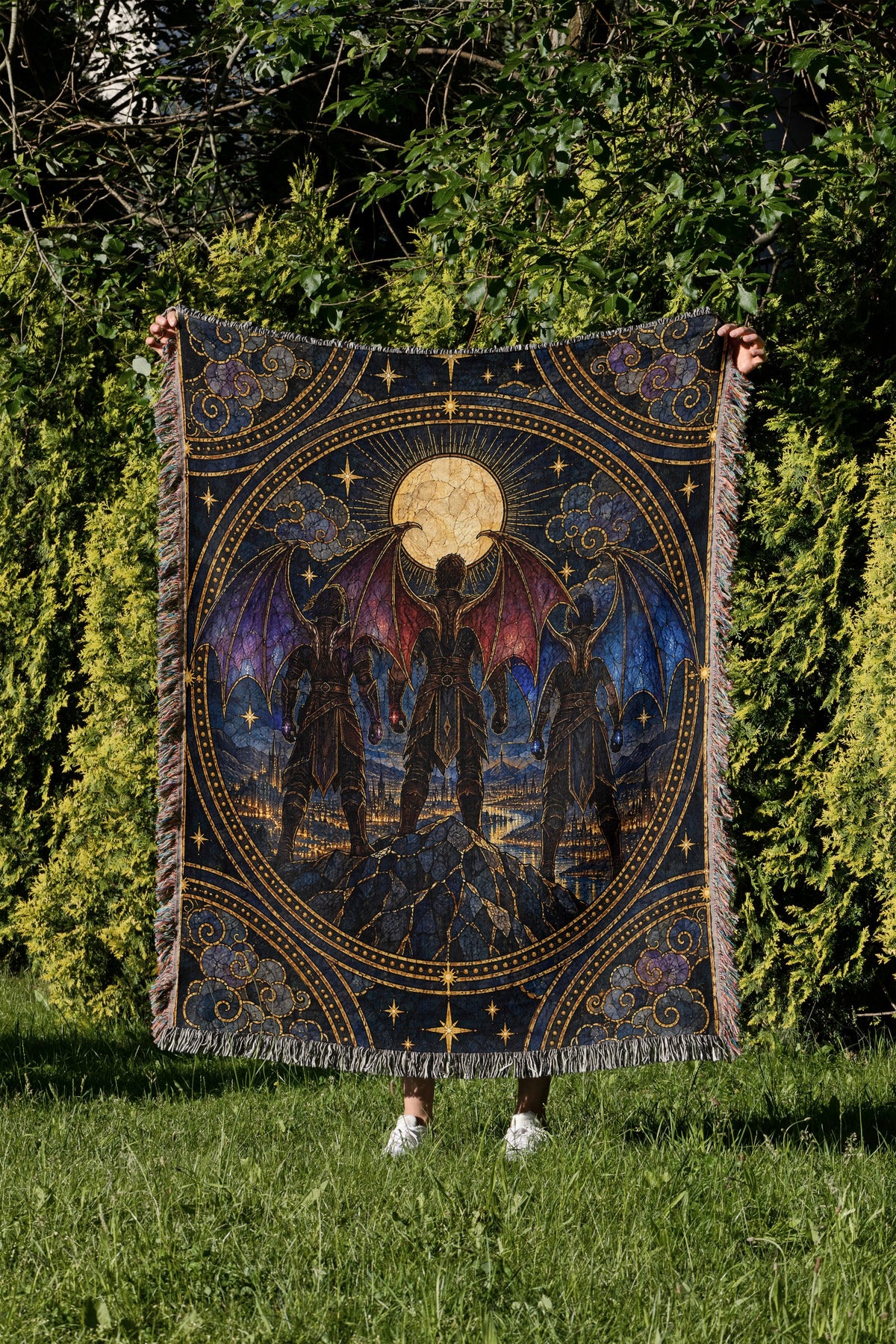 Illyrian Trio Stained Glass Woven Throw Blanket held up in a garden