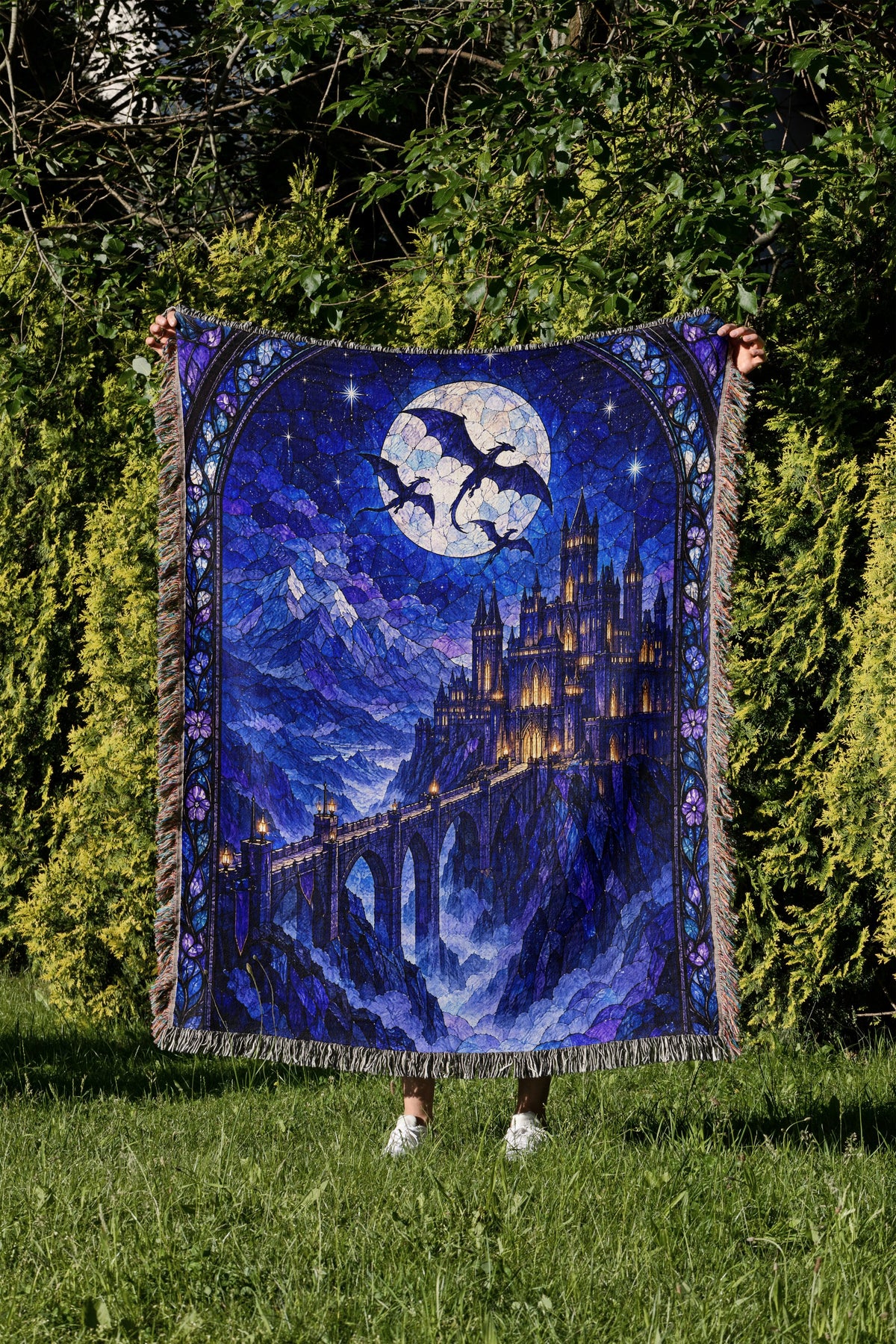 Basgiath by Night Stained Glass Woven Throw Blanket held up in a garden