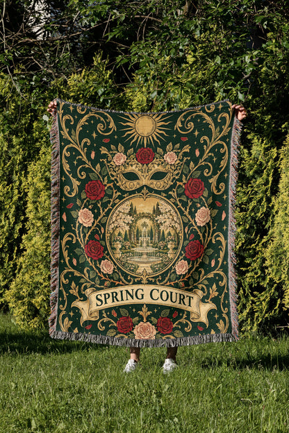 Spring Court Masquerade Crest Woven Throw Blanket held up in a garden