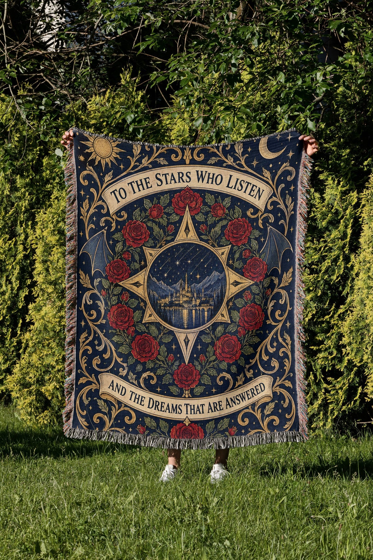 To The Stars Who Listen Rose Crest Woven Throw Blanket held up in a garden