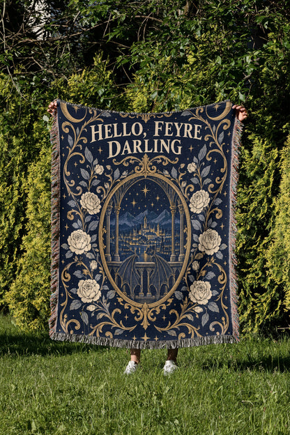 Hello Feyre Darling Crest Woven Throw Blanket held up in a garden