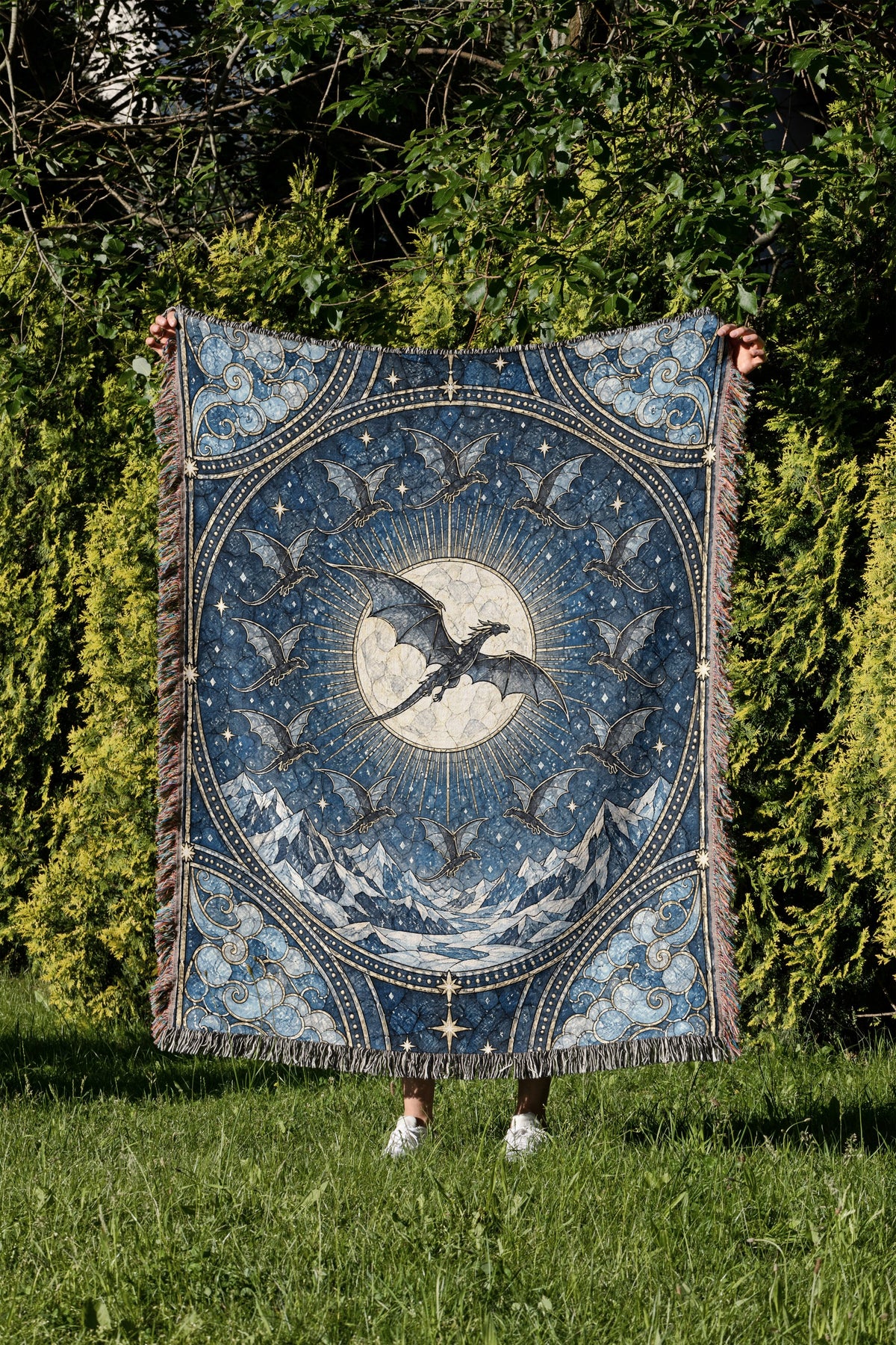 The Thirteen Stained Glass Woven Throw Blanket held up in a garden