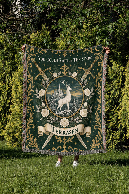 Terrasen Crest Woven Throw Blanket held up in a garden