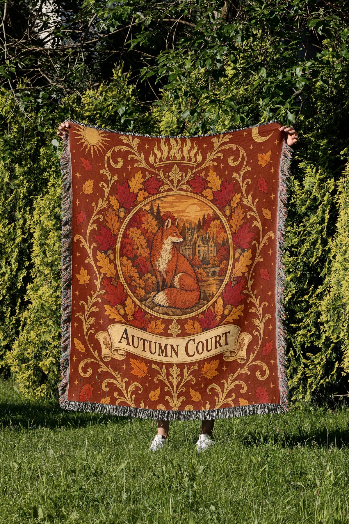 Autumn Court Fox Crest Woven Throw Blanket held up in a garden