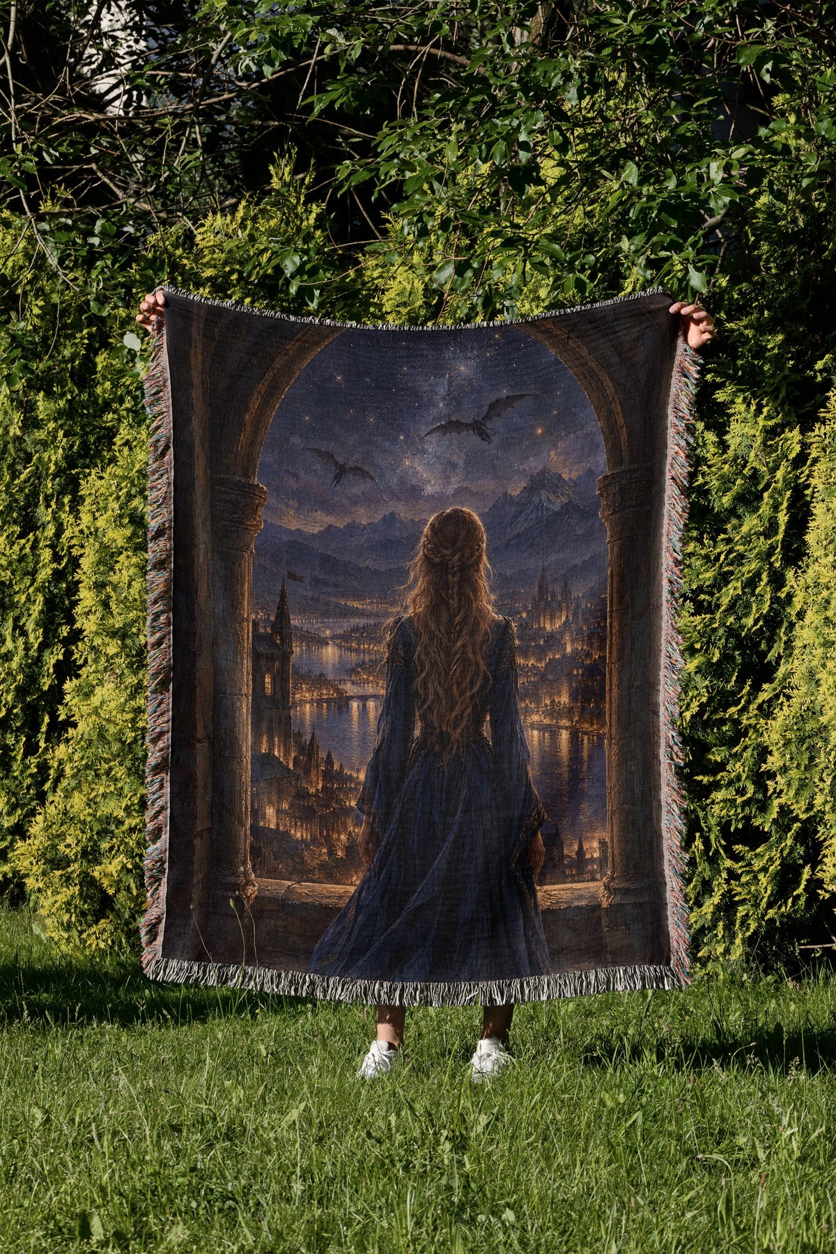 Feyre over Velaris Woven Throw Blanket held up in a garden