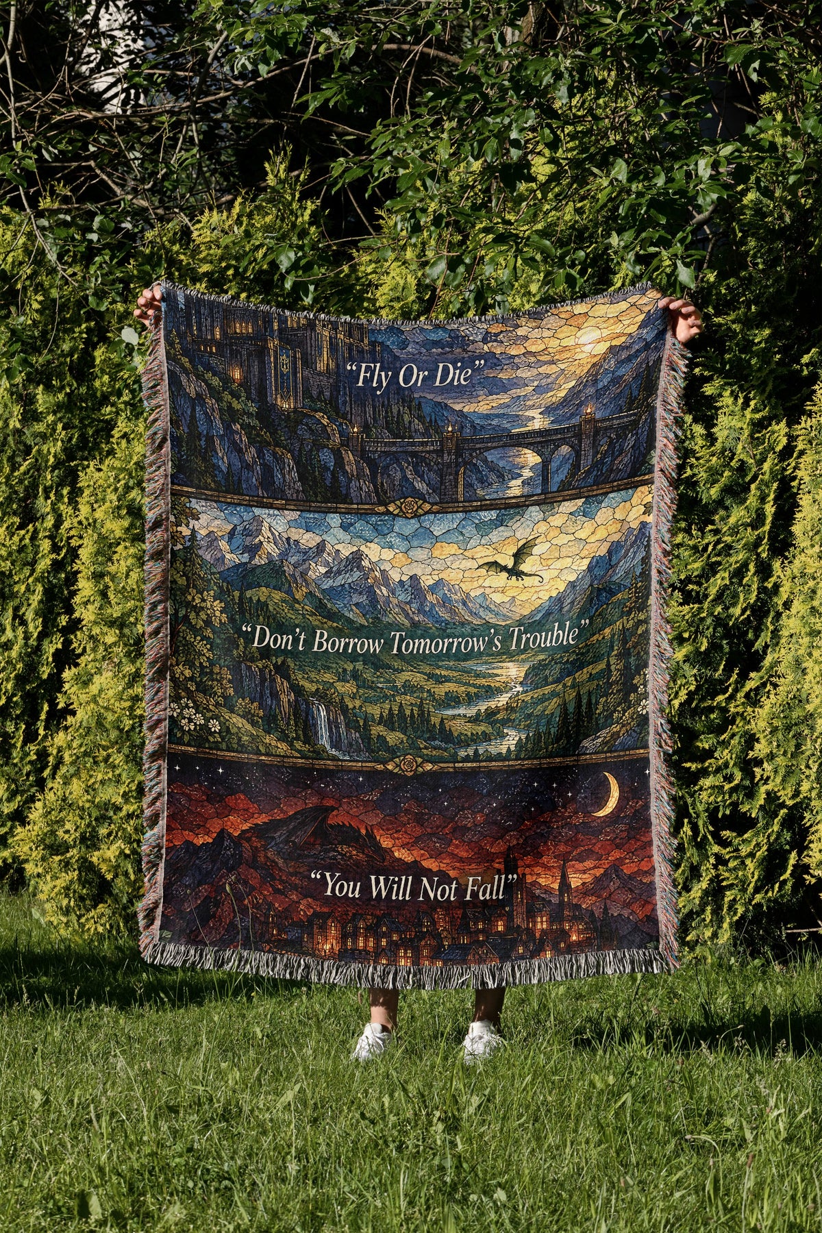 Empyrean Stained Glass Woven Throw Blanket held up in a garden