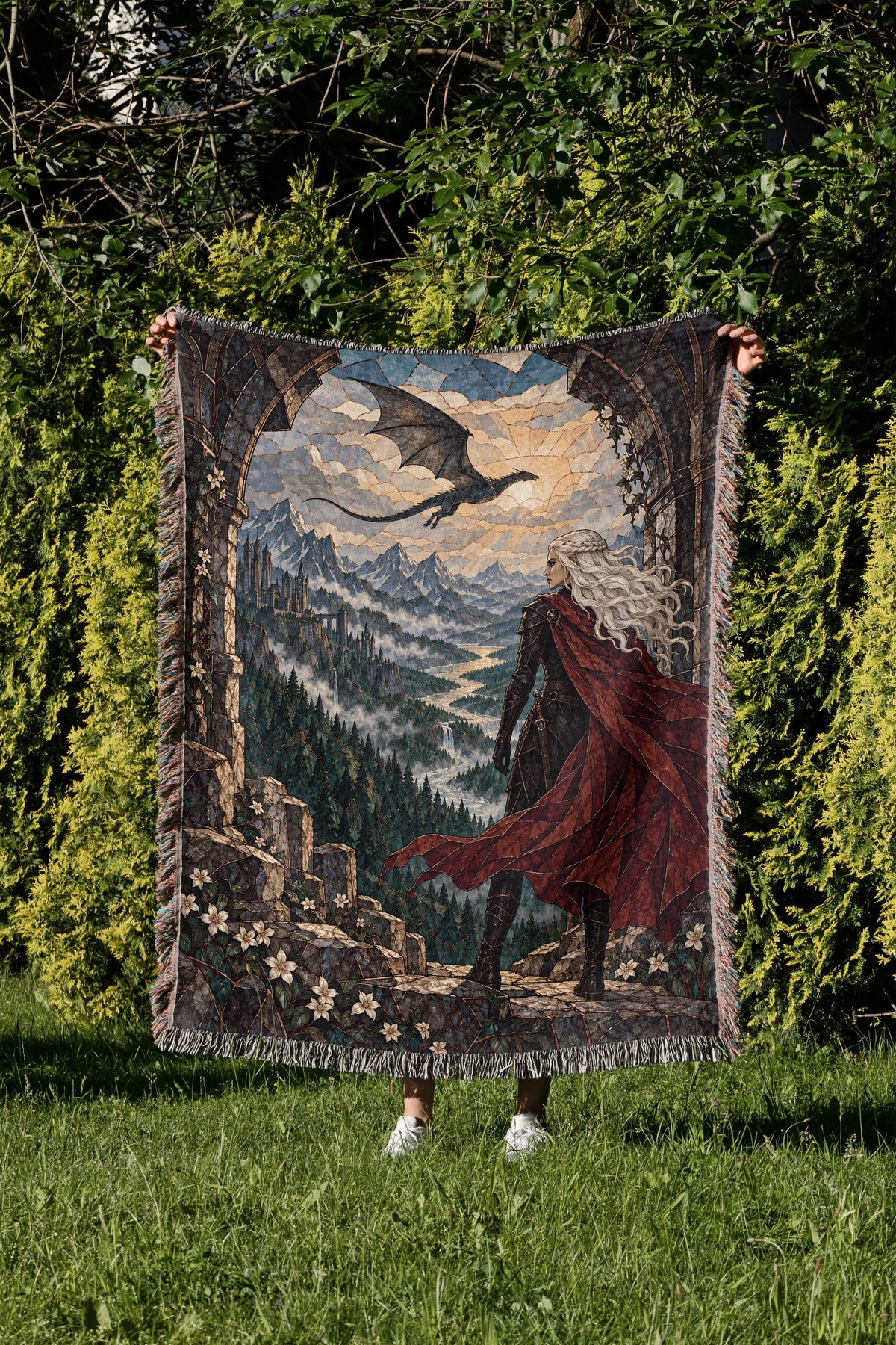Wyvern at the Mountain Pass Woven Throw Blanket held up in a garden