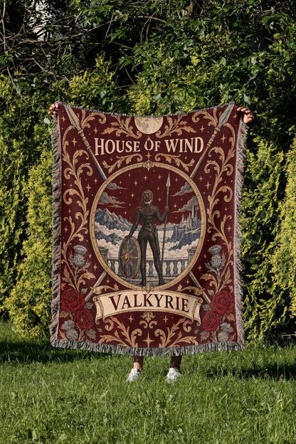 Valkyrie House of Wind Crest Woven Throw Blanket held up in a garden