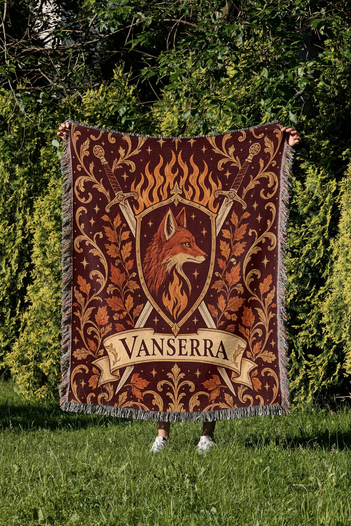 Vanserra Crest Woven Throw Blanket held up in a garden