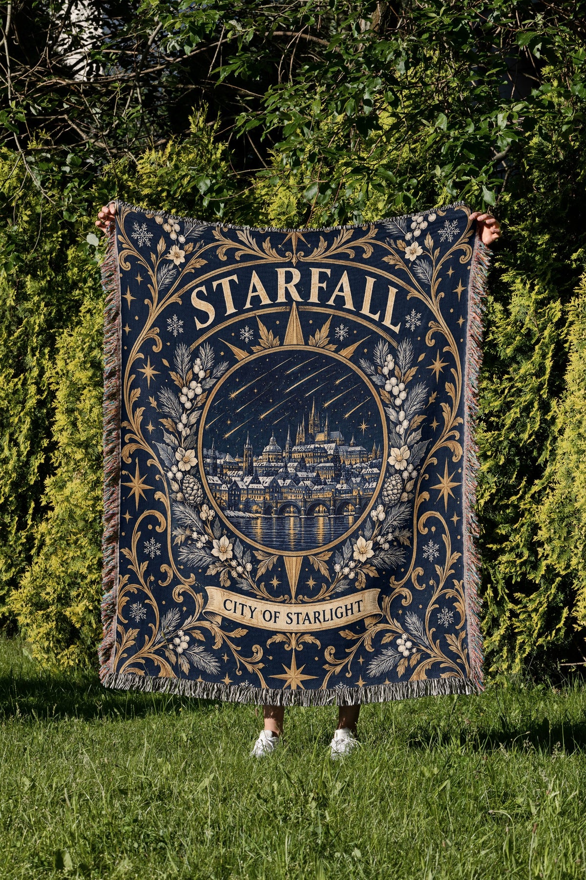 Starfall City of Starlight Crest Woven Throw Blanket held up in a garden
