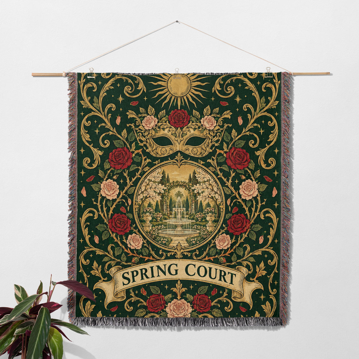 Spring Court Masquerade Crest Woven Throw Blanket hanging on a wall with a plant