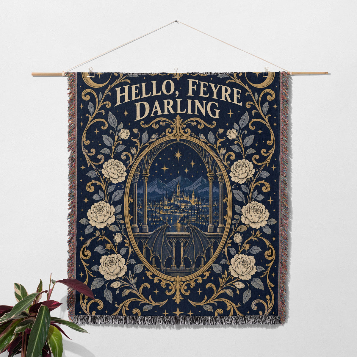 Hello Feyre Darling Crest Woven Throw Blanket hanging on a wall with a plant