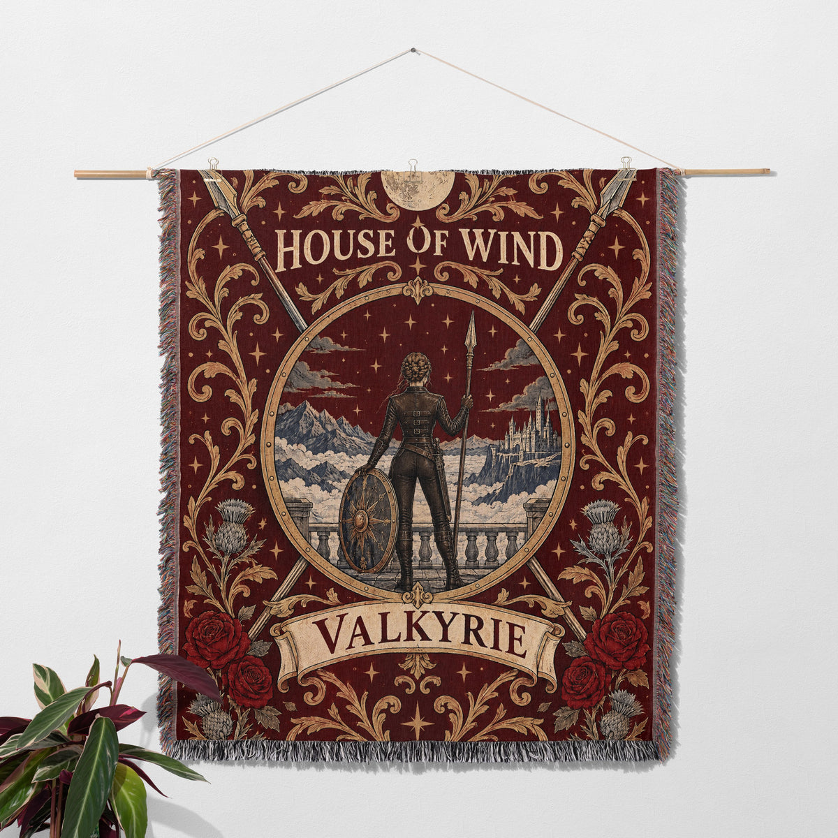 Valkyrie House of Wind Crest Woven Throw Blanket hanging on a wall with a plant