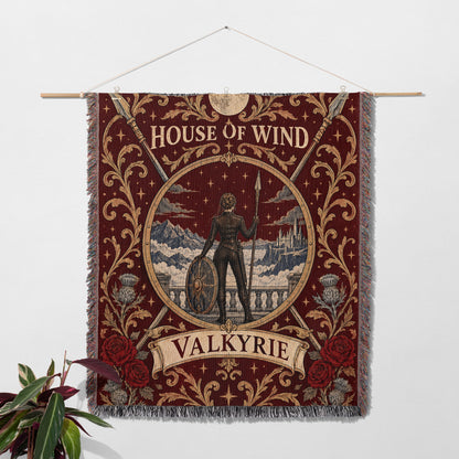 Valkyrie House of Wind Crest Woven Throw Blanket hanging on a wall with a plant
