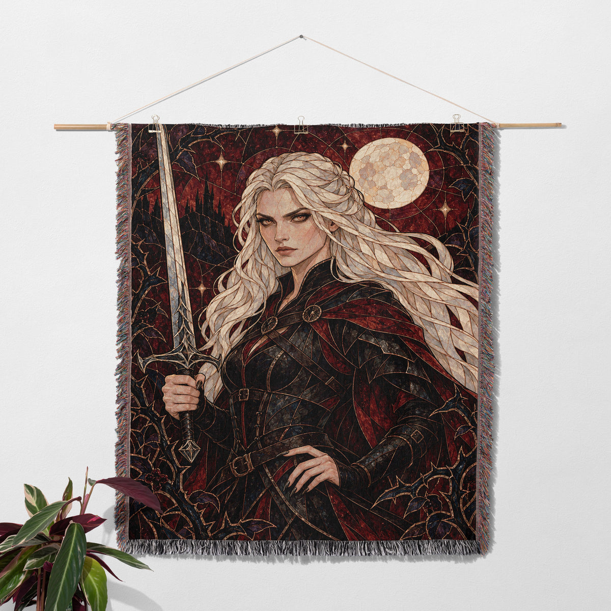 Iron Queen Woven Throw Blanket hanging on a wall with a plant