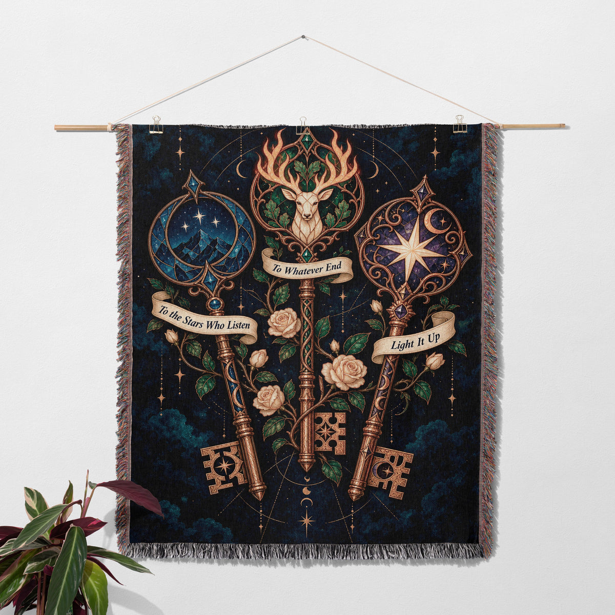 Bookish Maasverse Woven Throw Blanket hanging on a wall with a plant