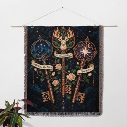 Bookish Maasverse Woven Throw Blanket hanging on a wall with a plant