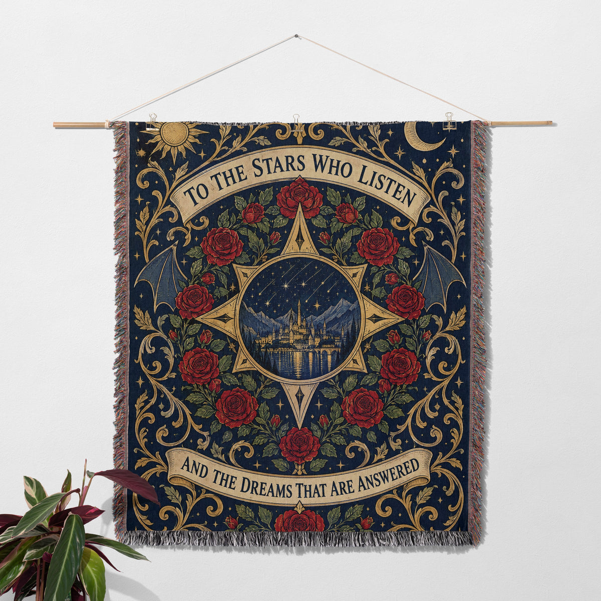 To The Stars Who Listen Rose Crest Woven Throw Blanket hanging on a wall with a plant