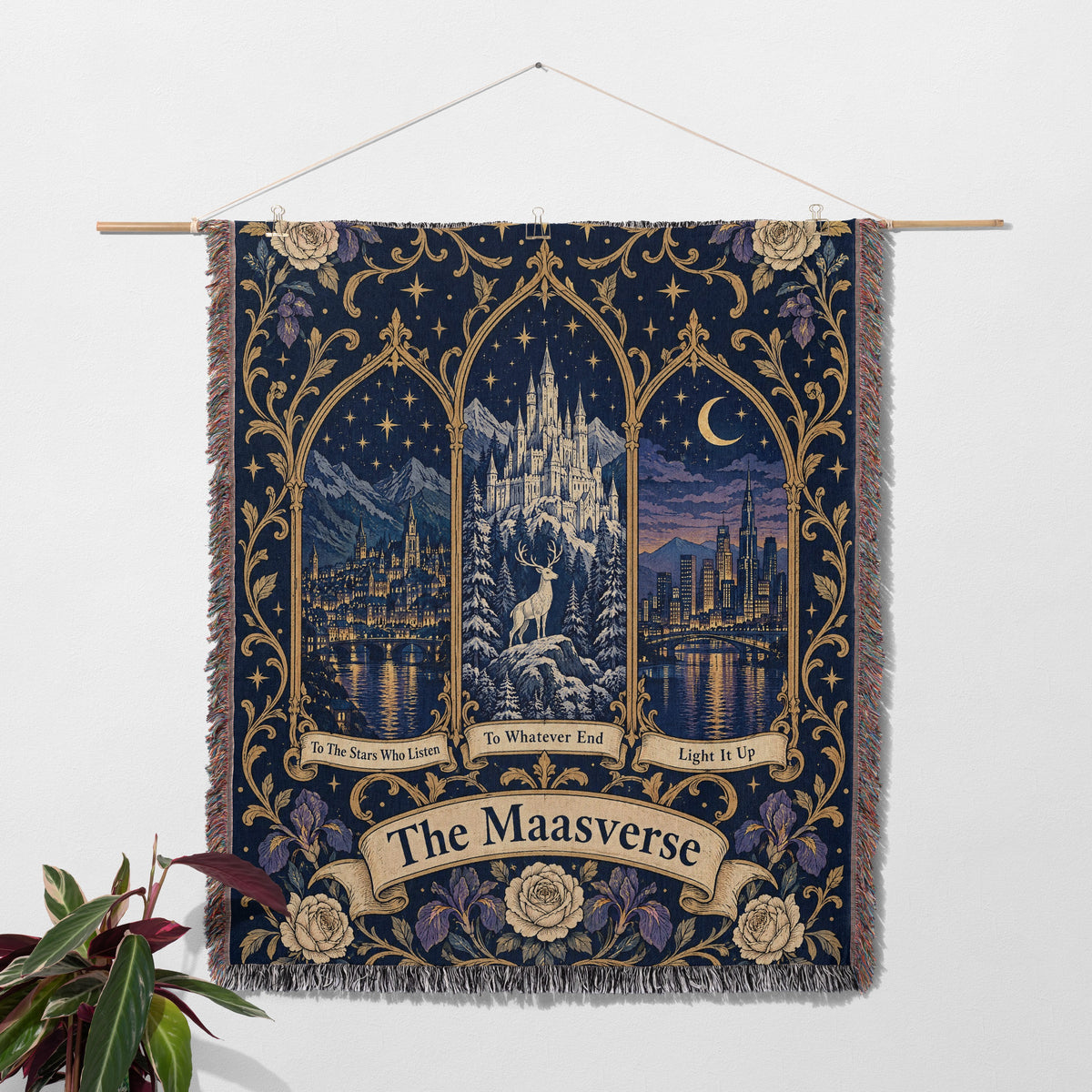 Maasverse Three Realms Crest Woven Throw Blanket hanging on a wall with a plant