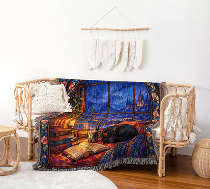 The Reader's Window Stained Glass Woven Throw Blanket on a rattan chair